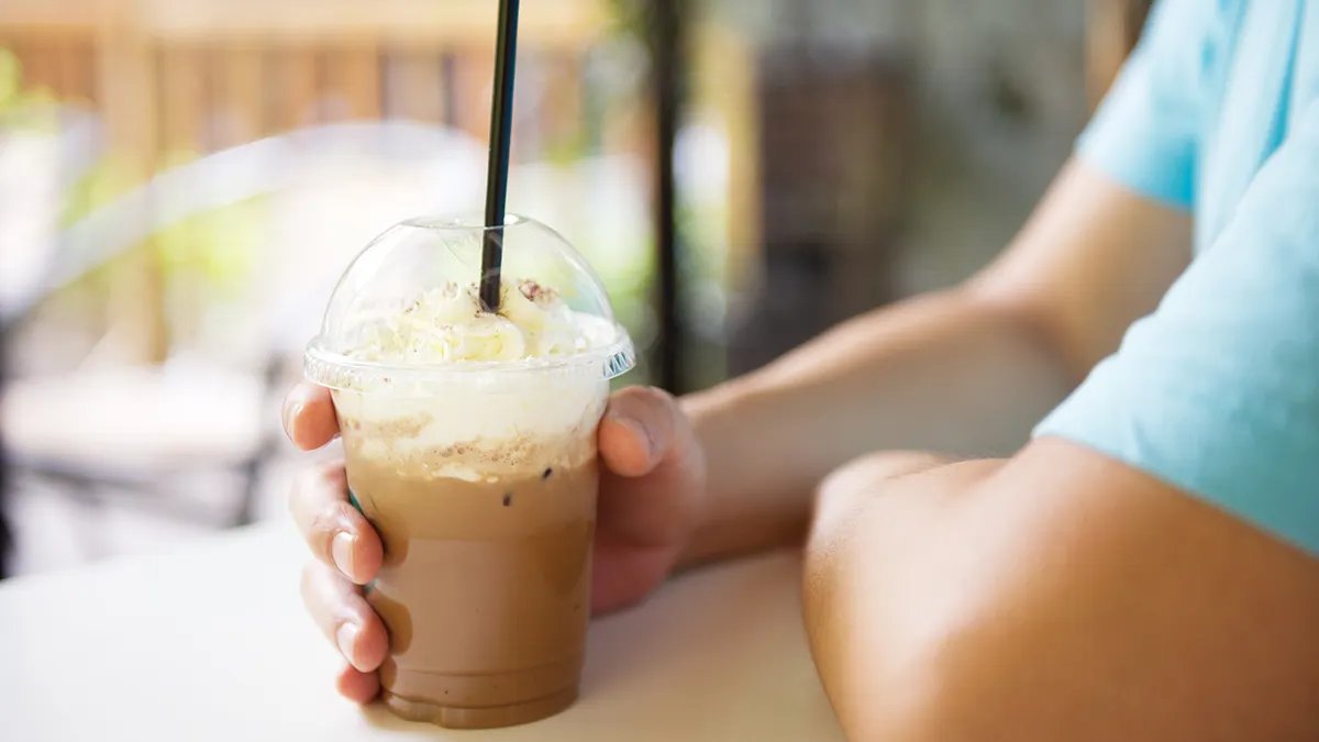 A person enjoying a refreshing iced coffee outdoors on a sunny day, symbolizing invigoration and alertness.