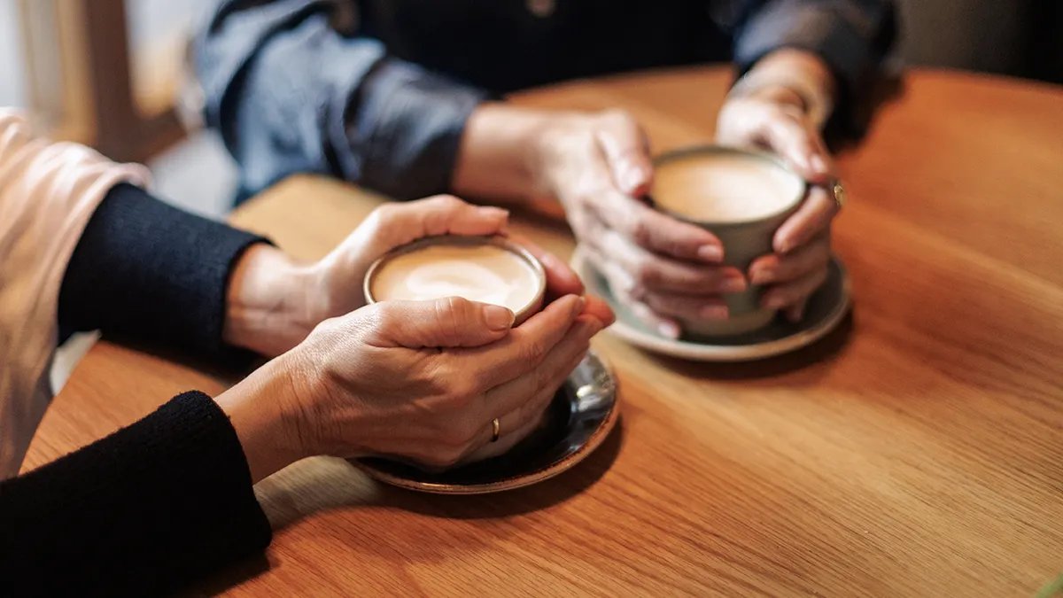 A person thoughtfully choosing between a variety of hot and cold drinks, representing the individual decision-making process for personal well-being.