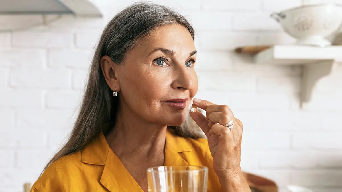 An older individual taking a supplement, representing a demographic that may benefit from CoQ10 due to natural decline.