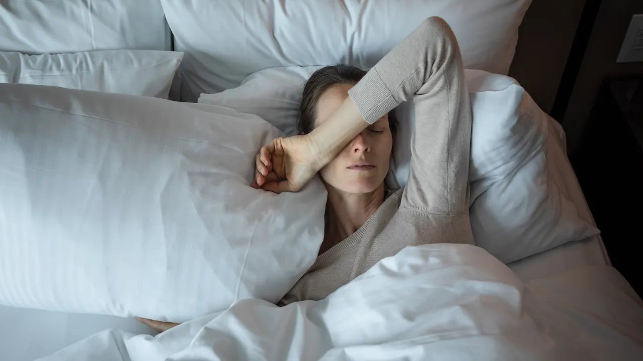 Woman awake late at night experiencing second wind insomnia Woman struggling to sleep in bed