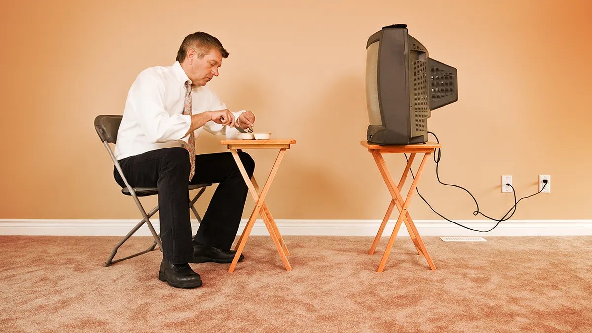 A person enjoying Hamburger Helper on a TV tray while watching television, illustrating the dish's convenience for couch dining