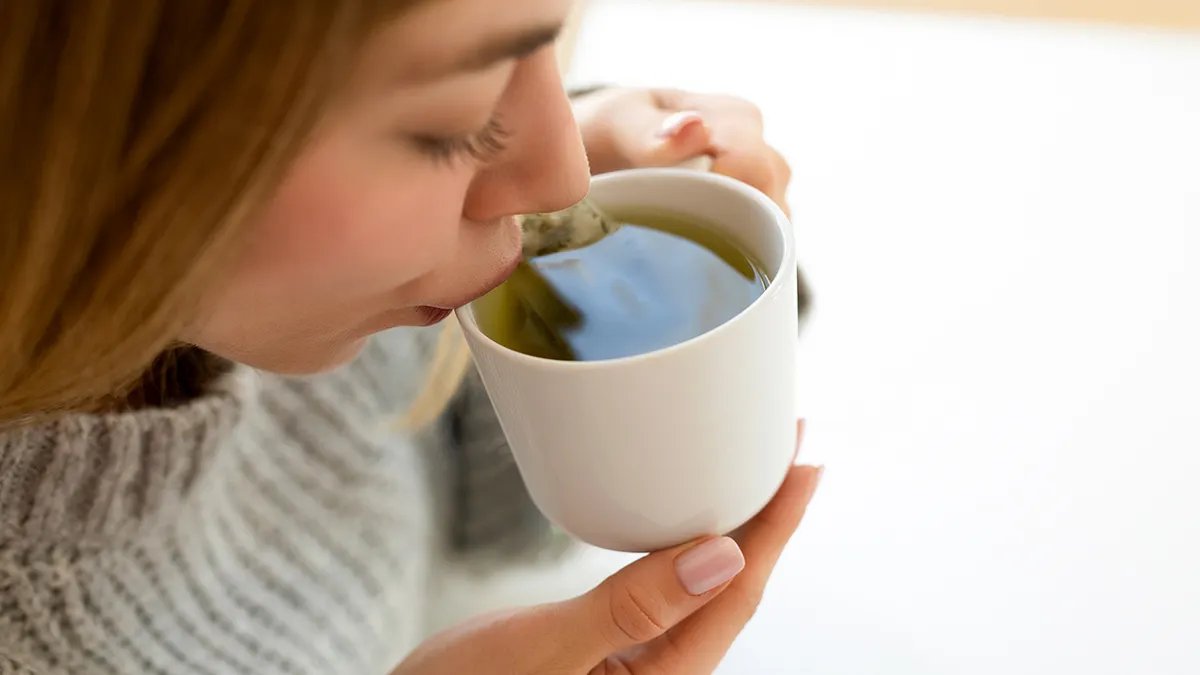 A person enjoying a moment of focus, possibly meditating or working, with a healthy snack and green tea nearby, symbolizing mental clarity.