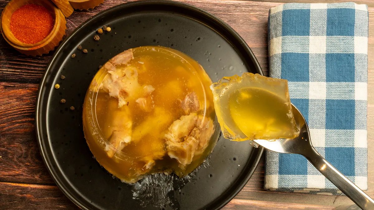 A sophisticated savory gelatin terrine, showcasing layers of vegetables and clarified broth.