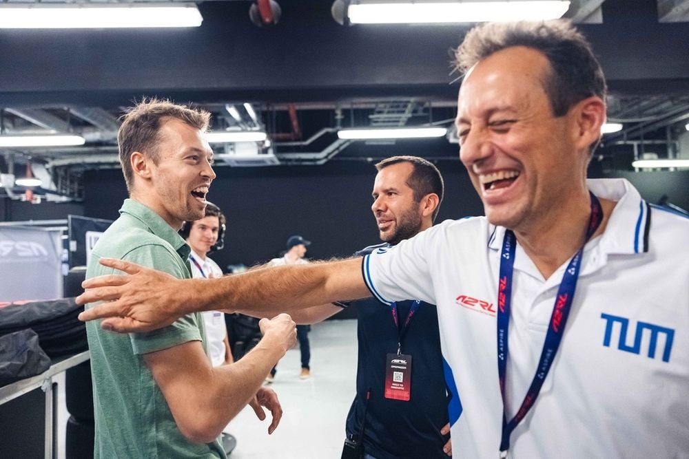 A team of engineers intently watches data screens in a pit garage during an A2RL race.