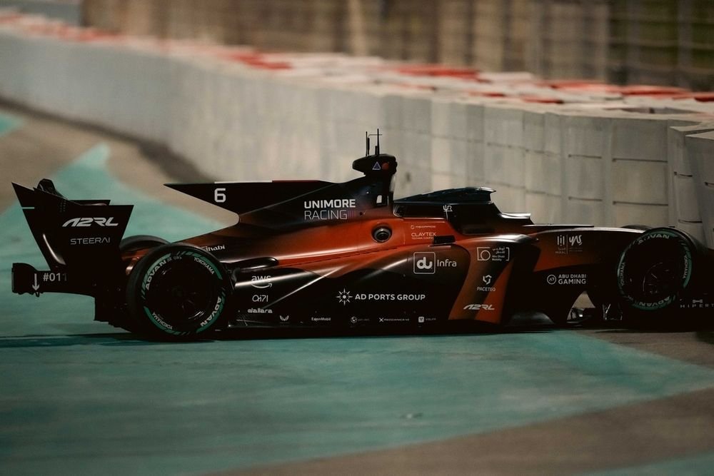 Autonomous racing cars speeding down a straight section of the track, showcasing their advanced aerodynamics.