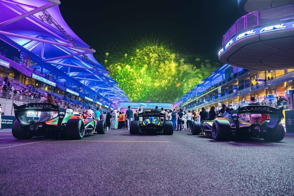 A team of smiling engineers celebrates after a successful race at the A2RL Finals, highlighting human triumph.