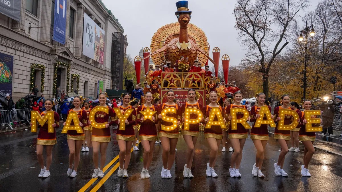A giant character balloon, possibly a new addition, soaring above the streets of New York City during the Macy's Thanksgiving Day Parade 2025.
