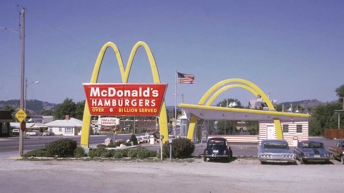 A McDonald's restaurant facade with people lining up, suggesting increased interest.
