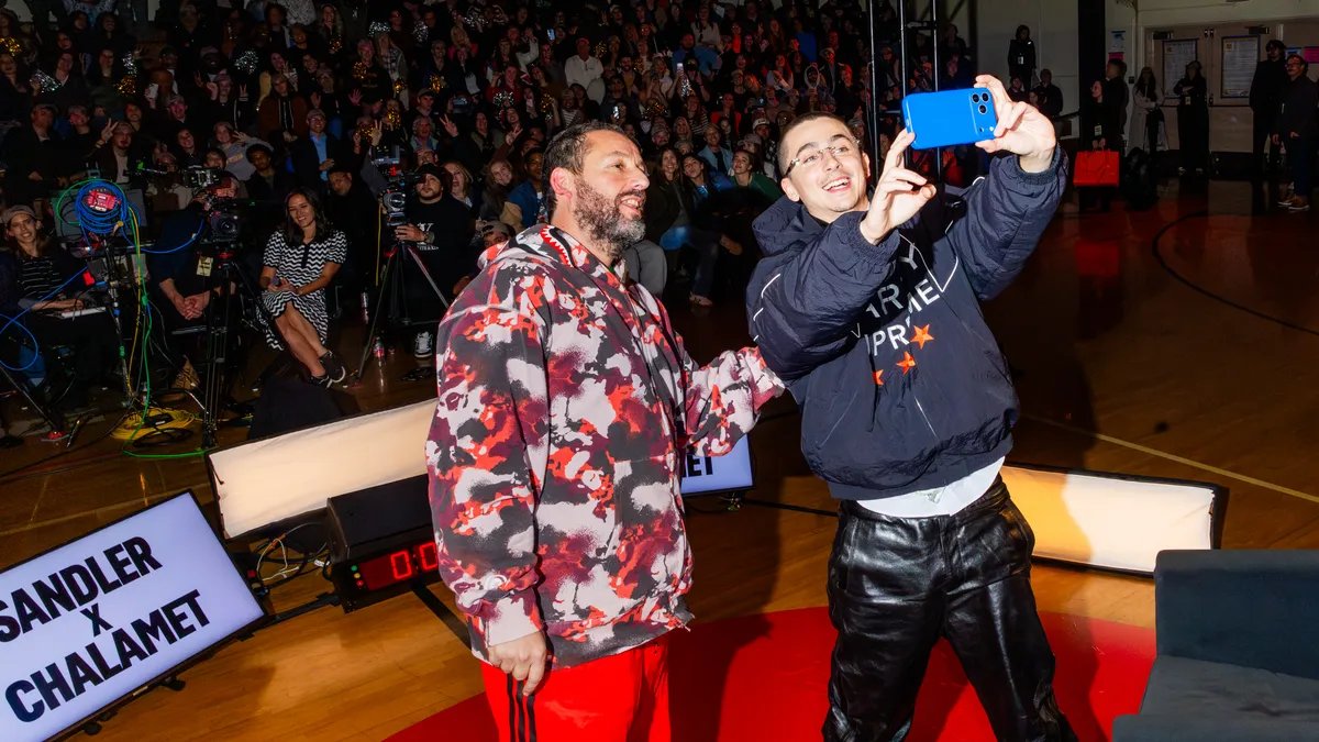 Timothée Chalamet and Adam Sandler engaged in a friendly basketball game, sharing a laugh on the court.