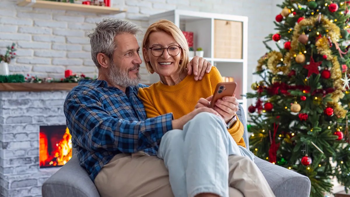 A family gathers around a Christmas tree, laughing and sharing stories as they decorate it together.