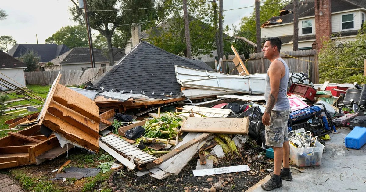 A neighborhood street showing homes with significant roof damage after a tornado.