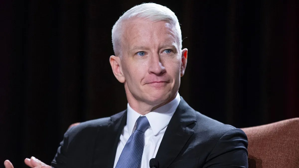 Anderson Cooper sitting in a podcast studio, visibly emotional.