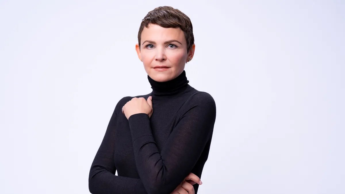 Ginnifer Goodwin smiling with a Zootopia promotional poster in the background.