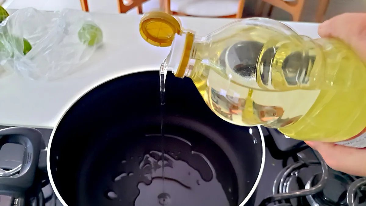 A person reading the label of a cooking oil bottle, highlighting the importance of being informed about ingredients.