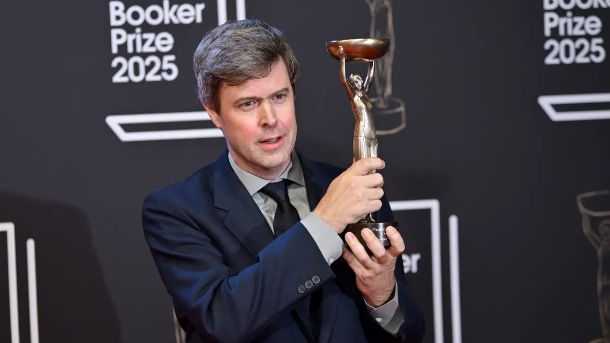 David Szalay holding the 2025 Booker Prize trophy with a look of humble triumph