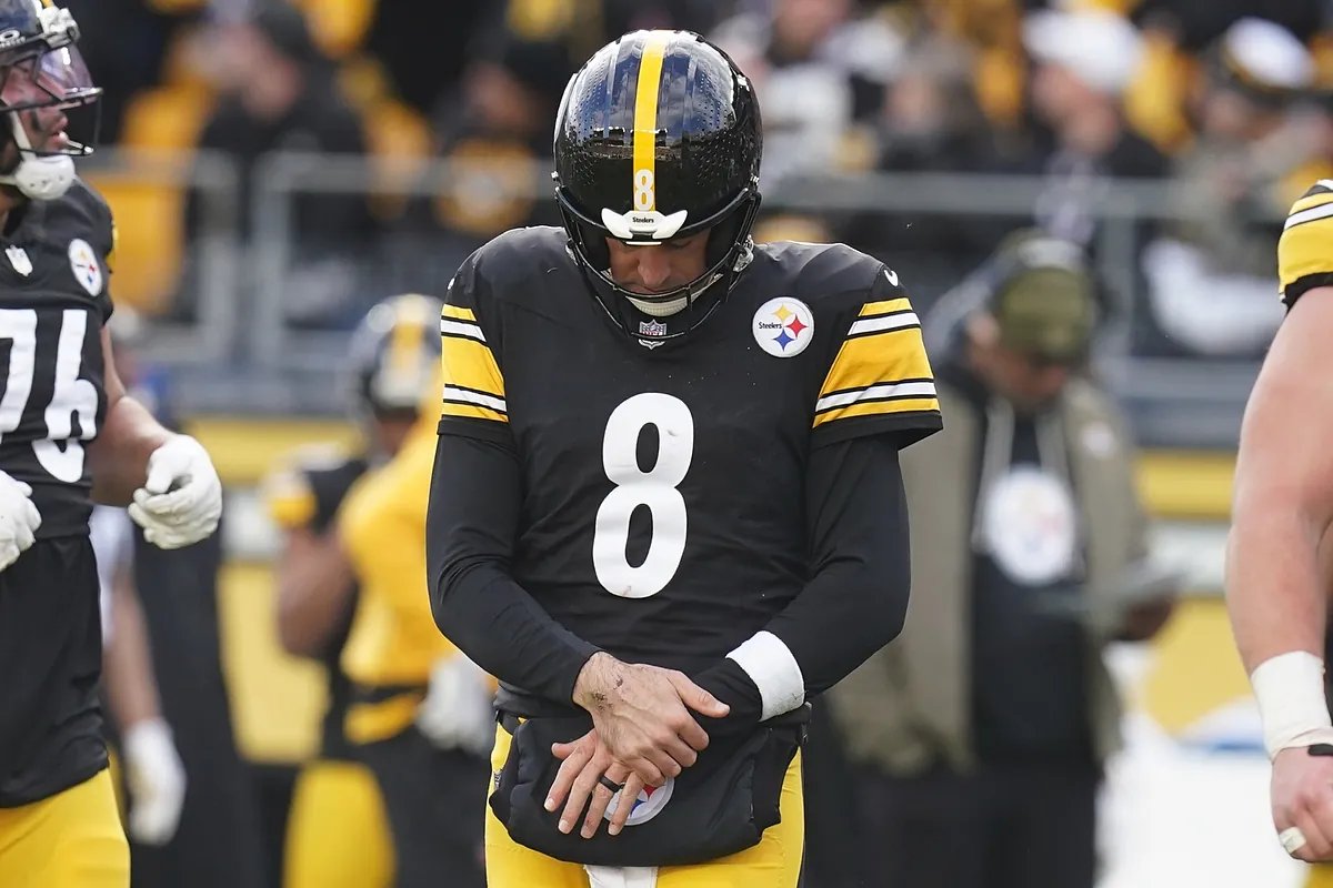 Aaron Rodgers looking concerned on the sideline after sustaining a wrist injury during an NFL game.