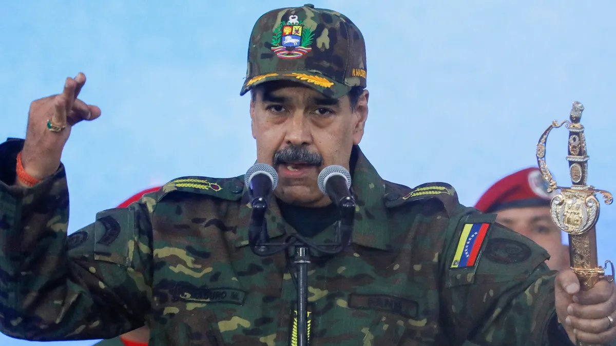 Donald Trump at a rally, gesturing and speaking to the crowd.