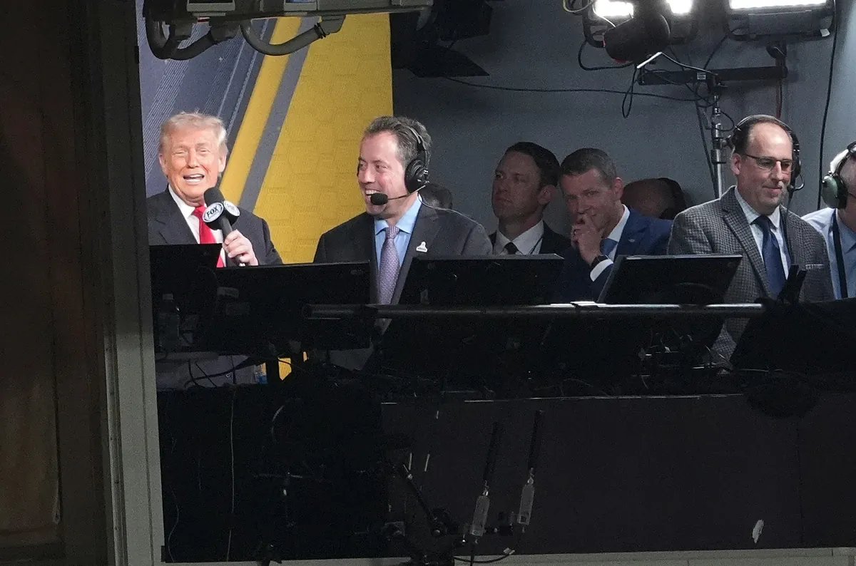 Donald Trump at an NFL game, looking intently at the field with a serious expression.