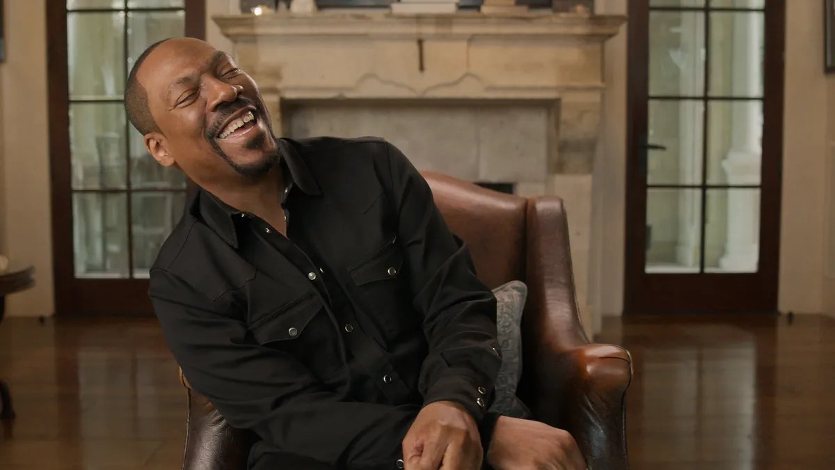 Eddie Murphy smiles broadly while accepting an award on stage.