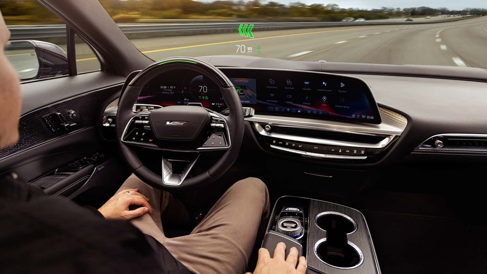 A Cadillac Escalade with Super Cruise engaged on a multi-lane highway, the blue light on the steering wheel visible.