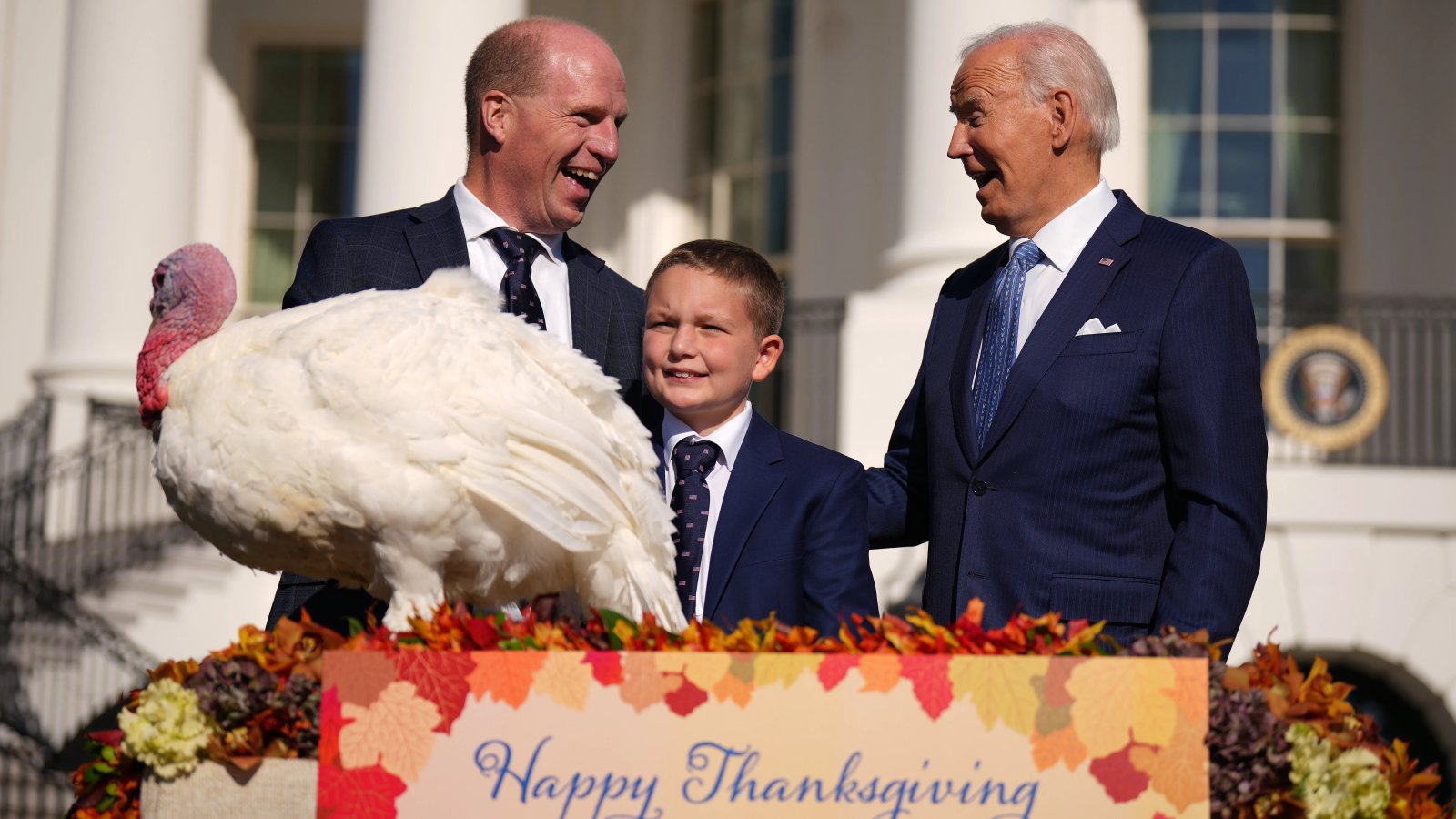 A turkey is being held by a person, presumably the President, at the White House.