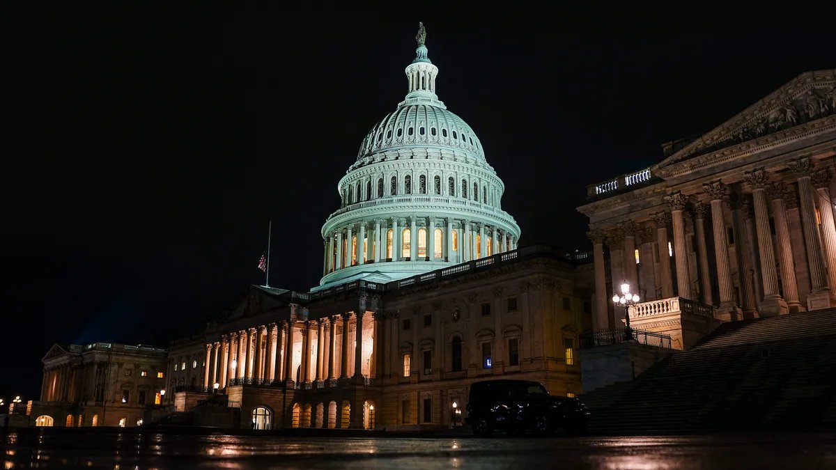 The Capitol Building, a symbol of the US government, standing against a clouded sky. 