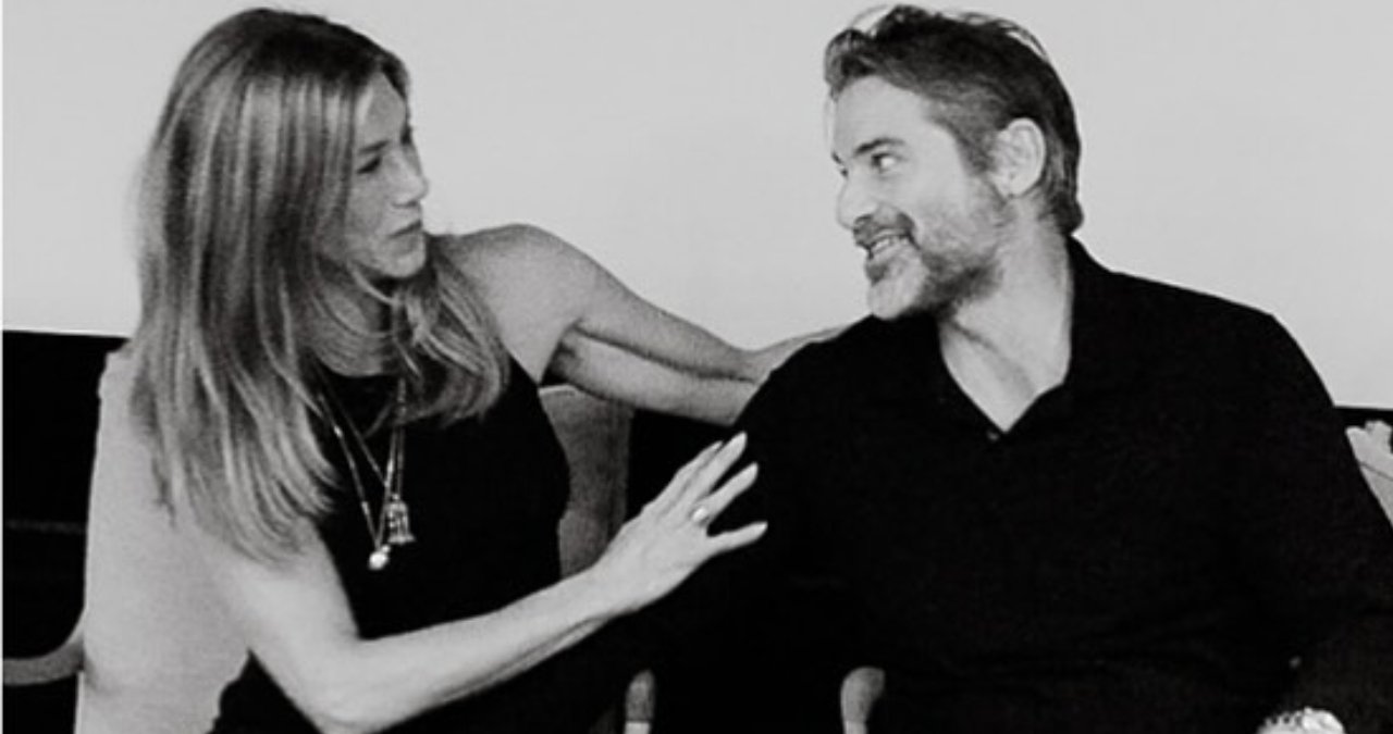 Jennifer Aniston and Jim Curtis together, smiling at a red carpet event.