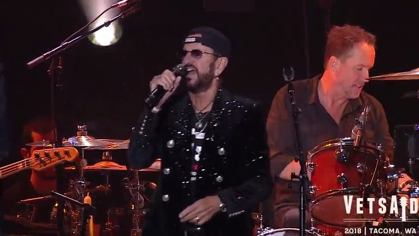 A laptop screen displaying a live streaming concert with a 'donate now' button visible, illustrating the online event.