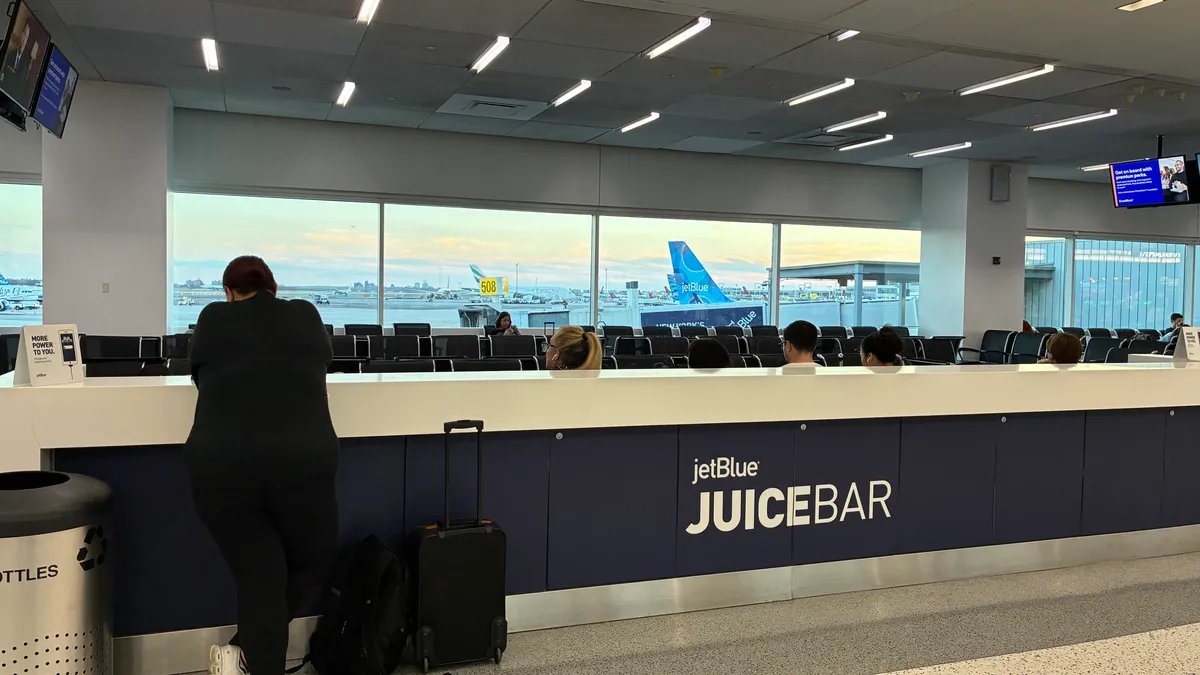 Busy airport terminal with travelers waiting, representing the impact of US flight cuts.