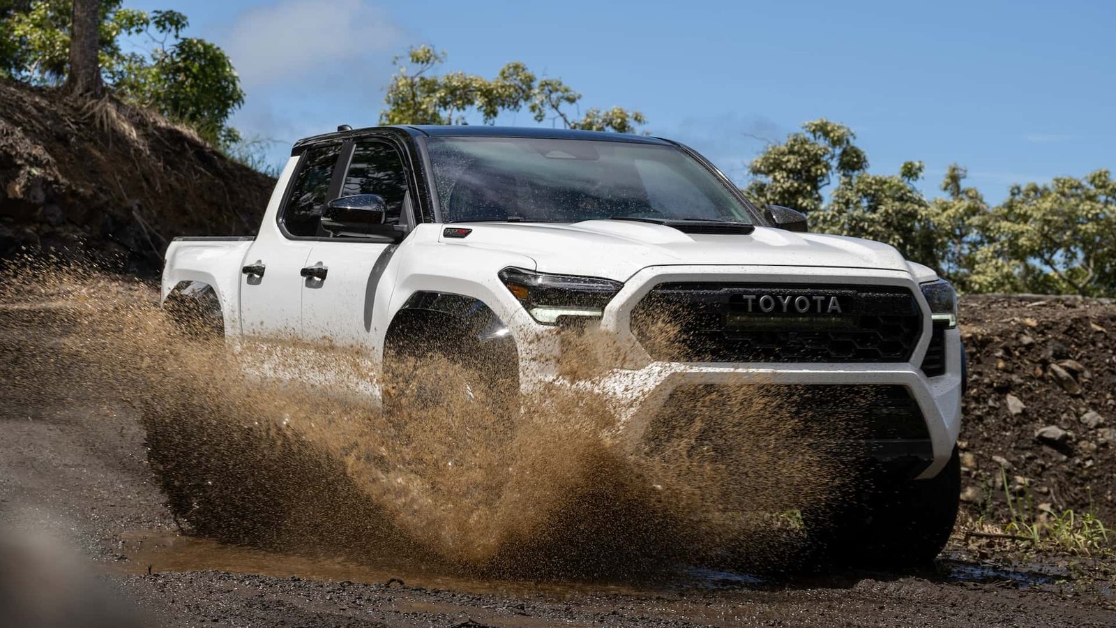 A rugged Toyota Tacoma parked on a dusty off-road trail at sunset, showcasing its durable build and adventure-ready stance.