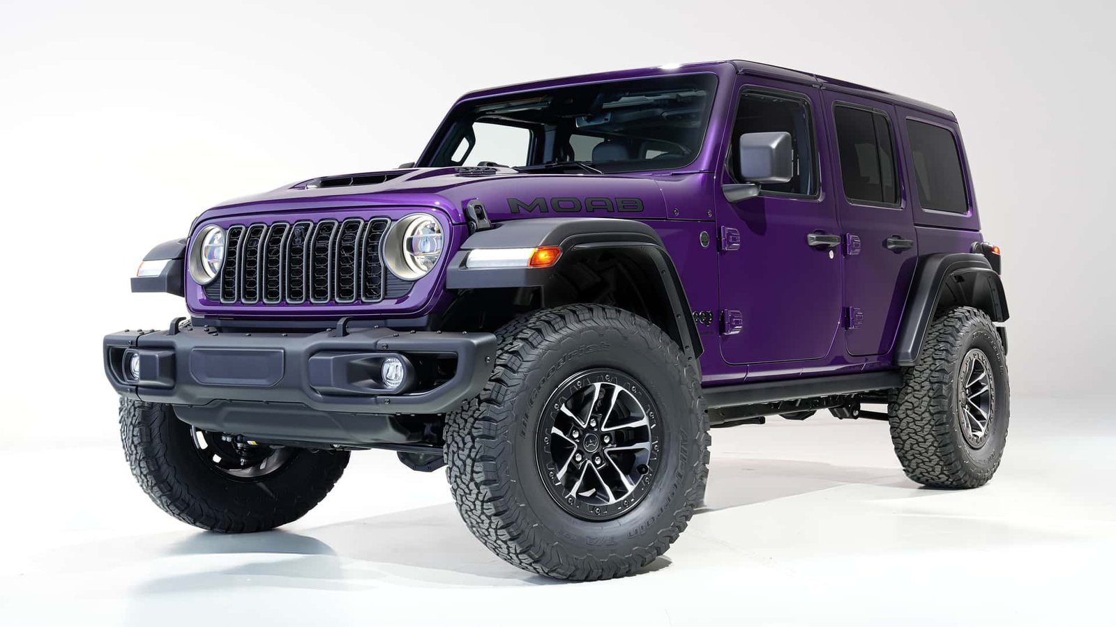 A powerful 2026 Jeep Wrangler V-8 navigating a rocky, off-road trail with a dramatic desert backdrop, showcasing its rugged design and capabilities.