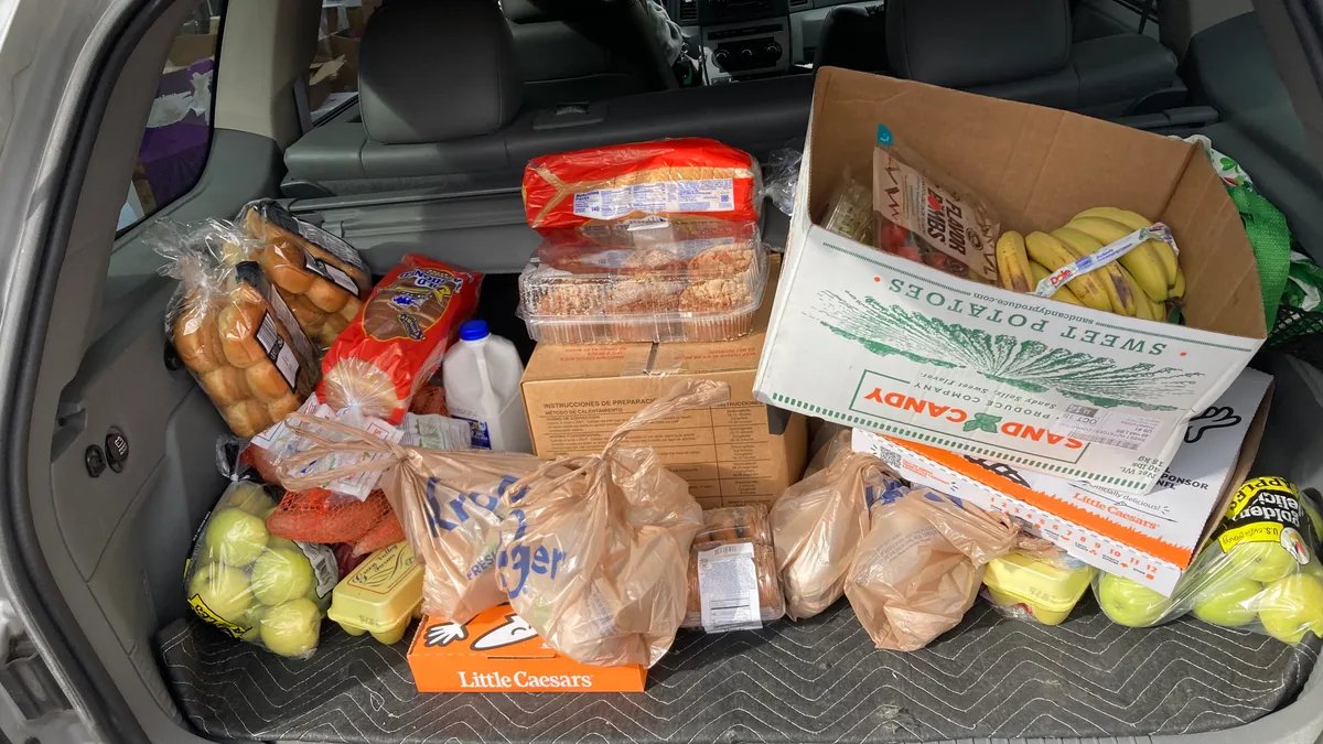 A long line of people waiting outside a food bank during a government shutdown, showing diverse ages and backgrounds.