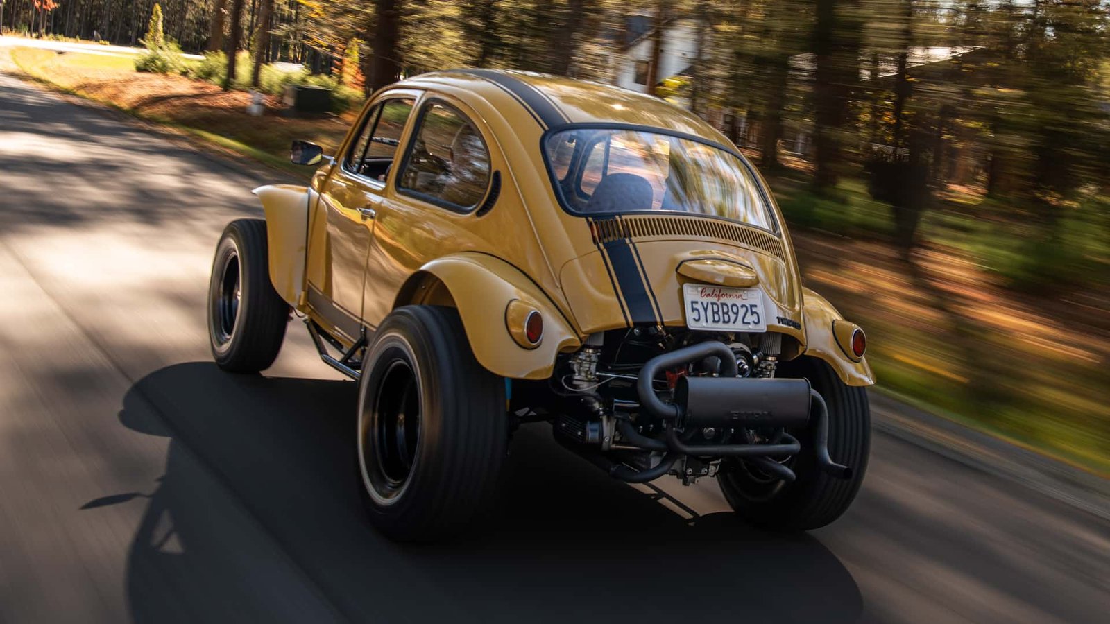 A vibrant yellow Baja Bug restomod kicking up dust on a desert trail, showcasing its custom suspension and large off-road tires.