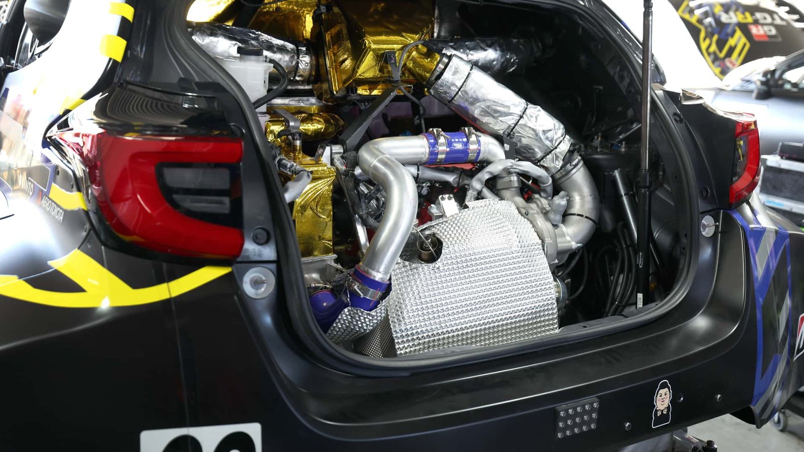 A sleek, futuristic Toyota concept engine bay showcasing a compact, high-performance four-cylinder engine with intricate turbocharging and cooling systems, surrounded by carbon fiber components.