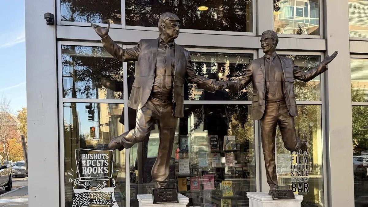 A statue depicting Donald Trump and Jeffrey Epstein holding hands is displayed in a gallery setting. The statue is bronze-colored and appears somewhat cartoonish.