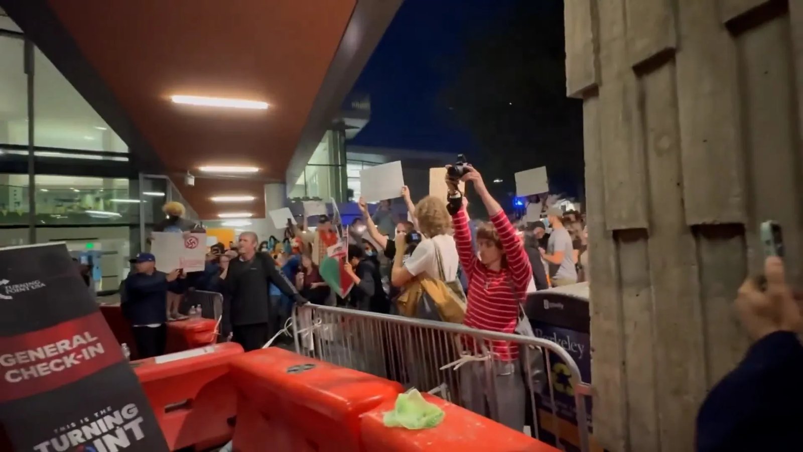A group of university police officers stand in a line, wearing protective gear, during a campus protest.
