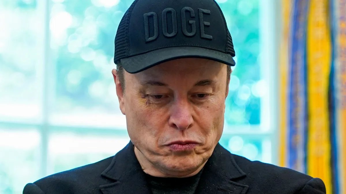 Elon Musk holding a Dogecoin plush toy, smiling.