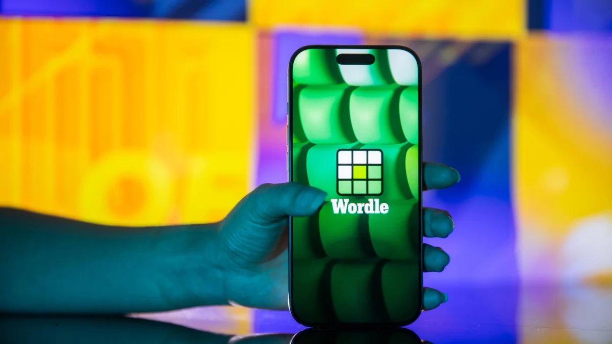 A person intently playing Wordle on a smartphone, with coffee and a newspaper nearby, depicting a common morning routine.