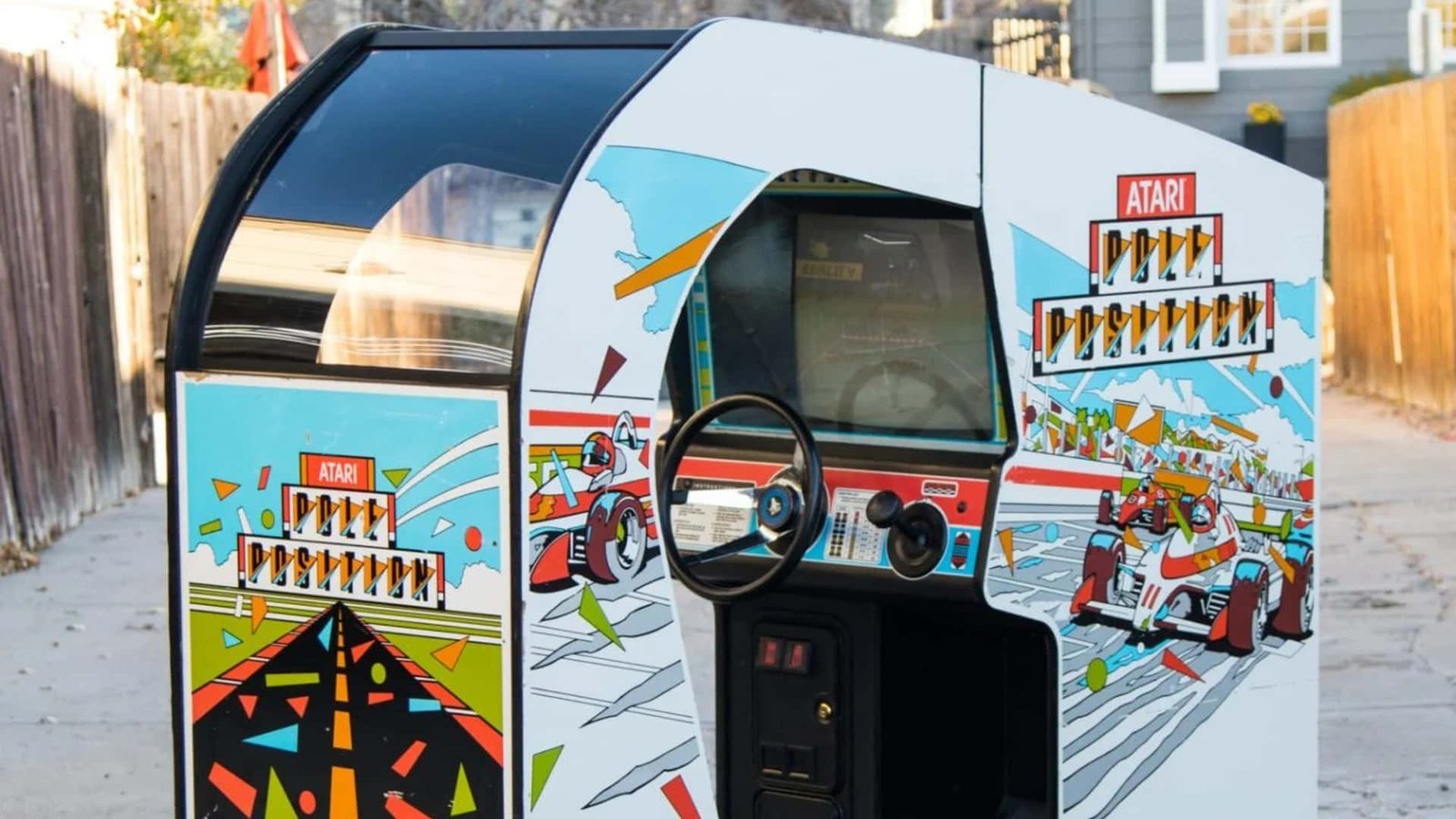 A perfectly restored Atari Pole Position sit-down arcade cabinet in a modern game room, glowing with retro charm.