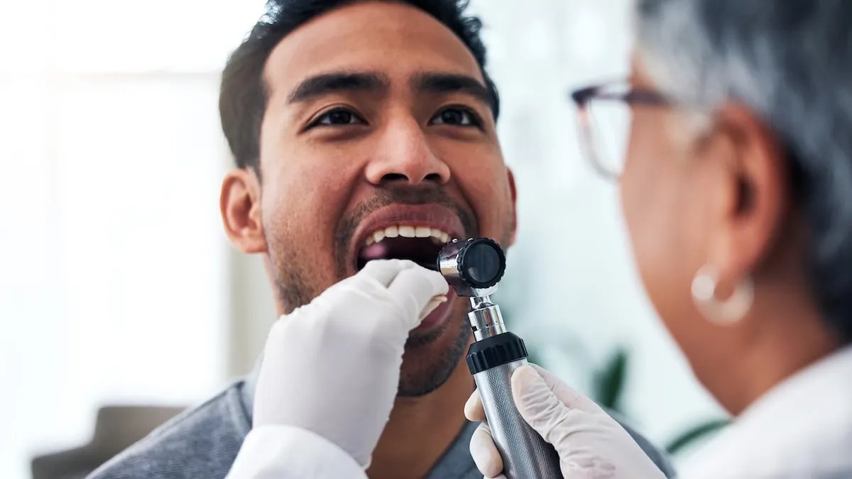 A person performing a self-exam of their tongue in a mirror.