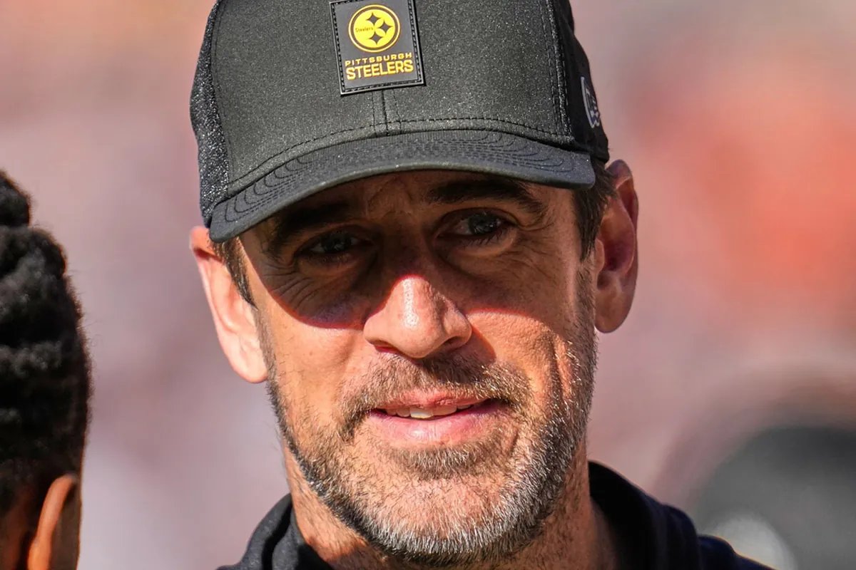 Aaron Rodgers on the sideline, looking determined during a Jets game.