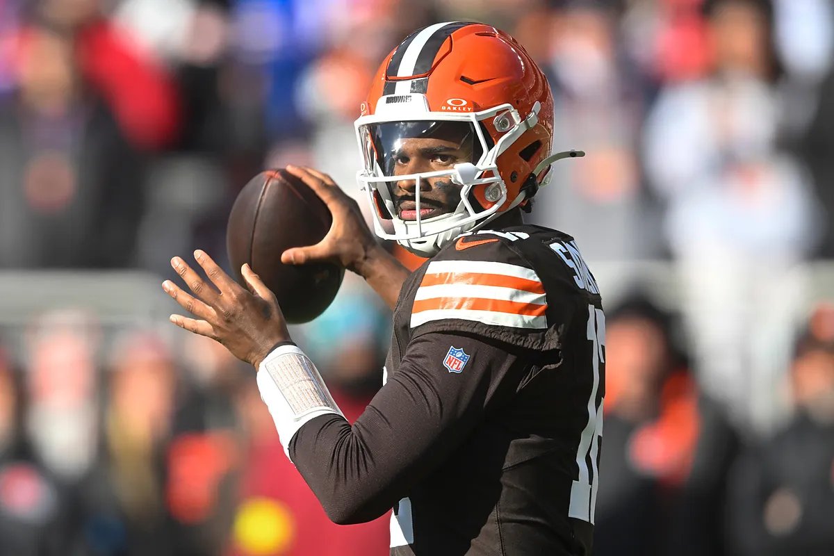 Shedeur Sanders intently watching a play from the sidelines during the Buffalo game, helmet in hand.