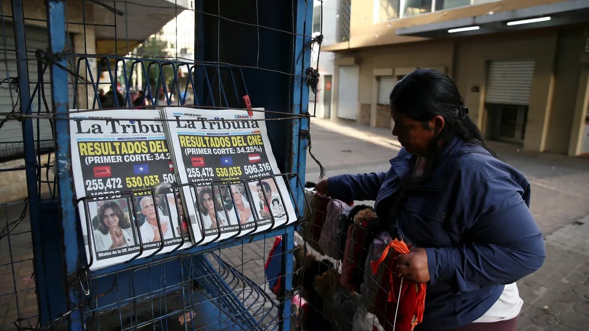 Crowd of supporters at a political rally, with signs and banners visible, cheering and waving.