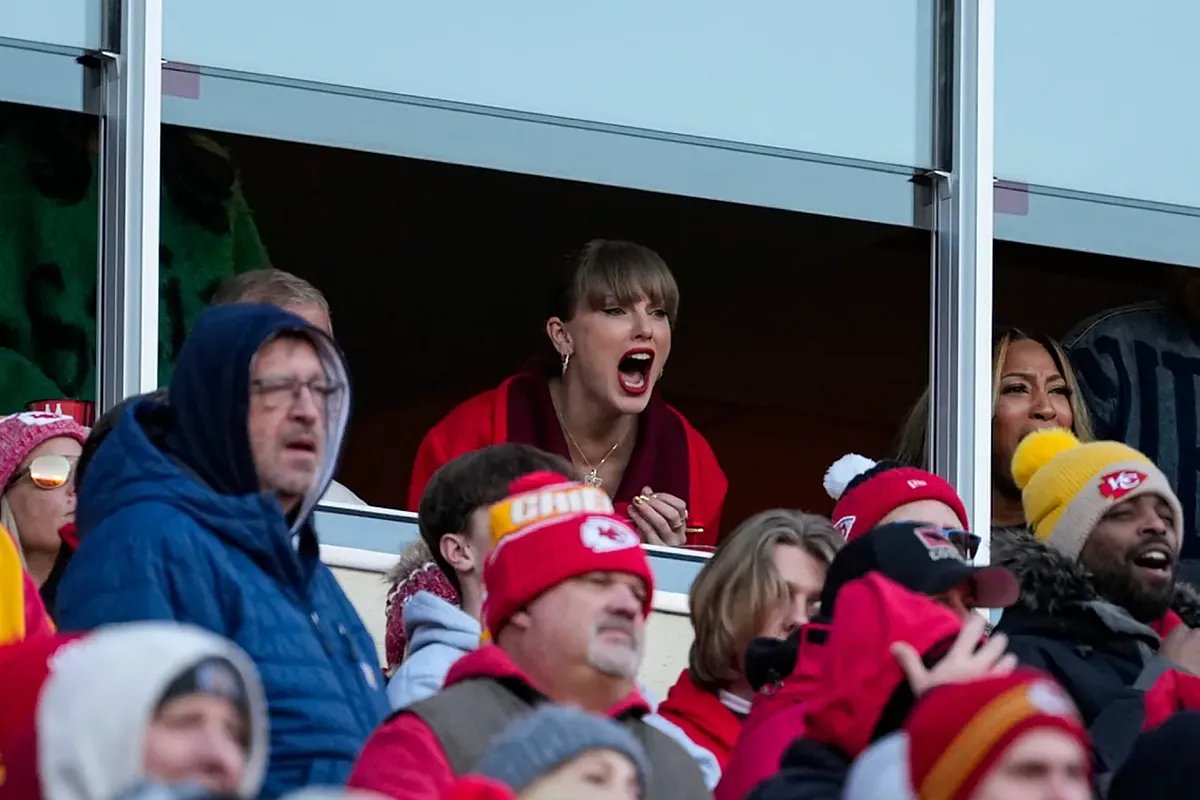 Taylor Swift and Travis Kelce looking at each other intensely during a public event, sparking speculation about their interaction.