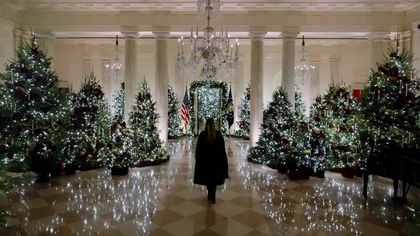 A close-up view of the White House facade adorned with elaborate Christmas wreaths, garlands, and golden lights at dusk.