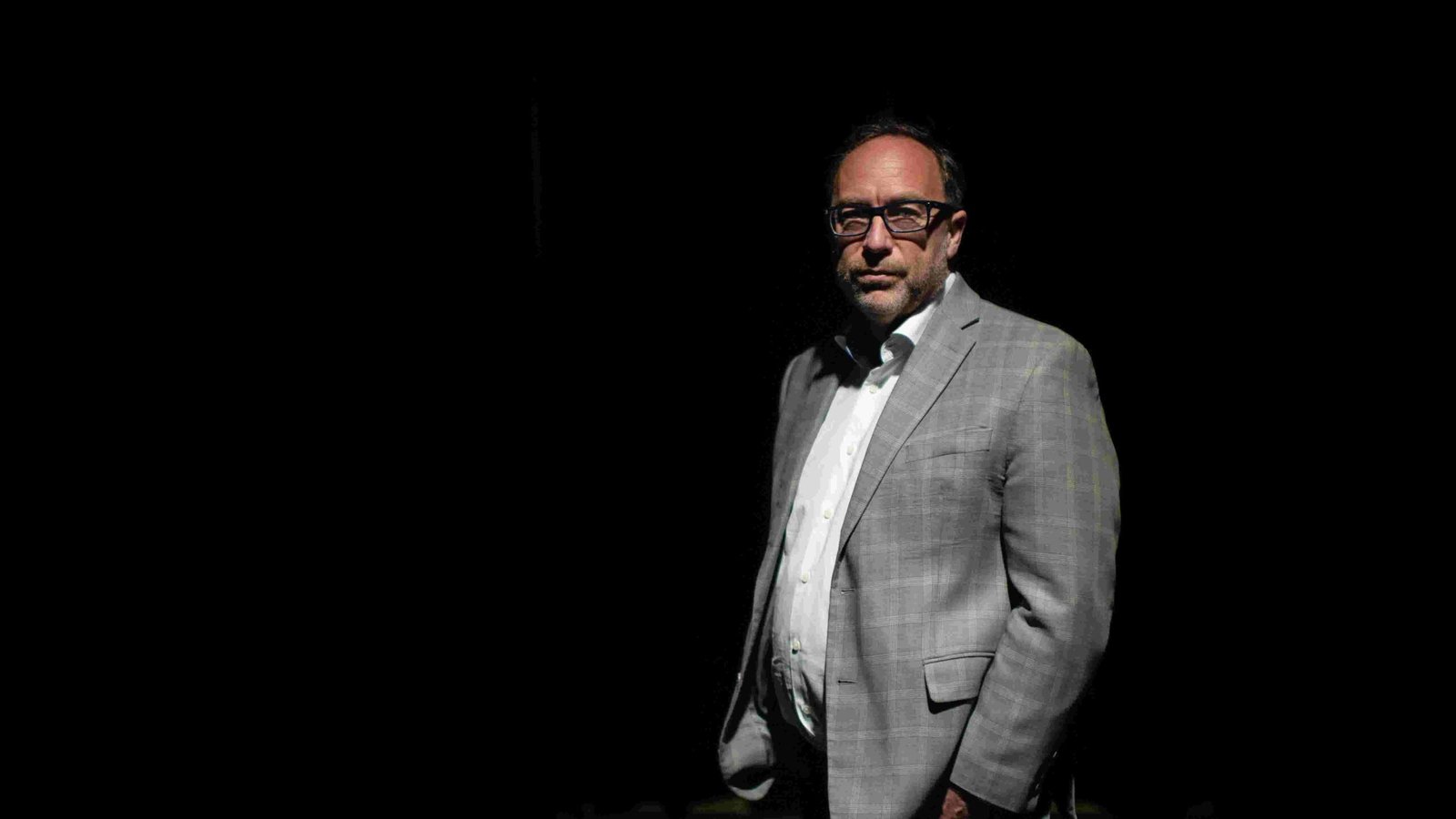 A stack of books with a magnifying glass focusing on one.