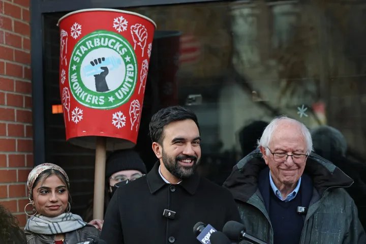 A close-up shot of Zohran Mamdani speaking to a striking Starbucks worker on the picket line.