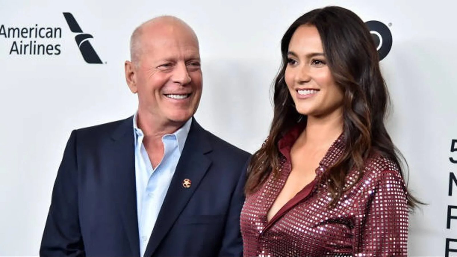 Emma Heming Willis gently holding Bruce Willis's hand, a tender moment captured.