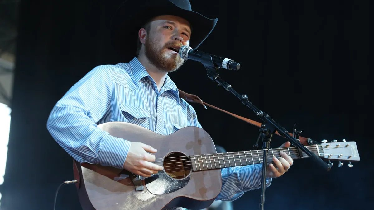Colter Wall performing on stage under dim lights, his voice resonating through the venue